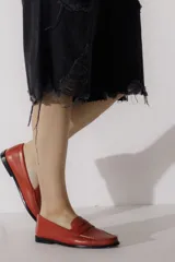 Mocasín de cuero vacuno color plateado, con costuras visibles en el empeine y suela de cuero negra.