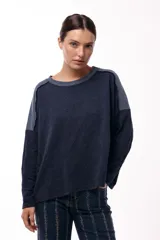 Remera de silueta relajada, confeccionada en tejido de punto con textura, de manga larga y cuello redondo. Presenta un diseño bicolor con paneles en contraste en los hombros y mangas.