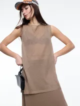 Musculosa de calce relajado y largo por debajo de la cadera, confeccionada en tejido translúcido con hilado de lurex que aporta un brillo sutil. Presenta aberturas laterales y diseño sin mangas.