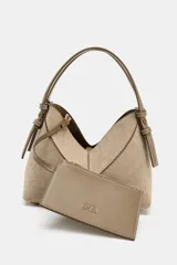 Bolso mini shopper de diseño trenzado en color beige, con asas de mano y correa bandolera extraíble en tono marrón. Presenta detalle de pespuntes en contraste y cierre interior con cremallera.