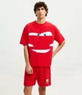 Pijama corto de hombre confeccionado en algodón, compuesto por una remera de manga corta con cuello redondo y estampa frontal de Rayo McQueen, y una bermuda roja a juego con cintura elástica.