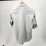 Camisa de vestir de algodón color gris claro con finas rayas verticales negras, cuello italiano, manga larga con puños abotonados y logo bordado en el pecho. Marca Duxon Originals.