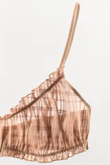 Bralette de escote redondo con tirantes finos ajustables, confeccionado en tejido semitransparente con diseño de elásticos fruncidos y acabados en volantes a tono.