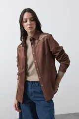 Sobrecamisa de gamuza color marrón con bordados decorativos estilo western en la zona de los hombros y cierre frontal con botones metálicos.