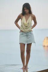 Falda mini de denim de tiro medio y lavado claro, con detalles de roturas y bajo deshilachado sin costuras. Cuenta con bolsillos delanteros y cierre frontal con cremallera y botón.