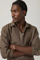 Camisa de manga larga color marrón oscuro, con cuello clásico y cierre frontal de botones. Se lleva abierta sobre una remera blanca de algodón acanalado.