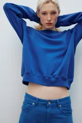 Buzo rojo de cuello redondo y manga larga, con efecto lavado y detalle de costura triangular en el cuello.