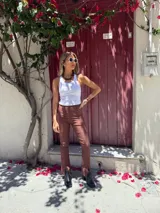 Pantalón marrón acampanado de gabardina elastizada con ojalillos metálicos en los laterales.