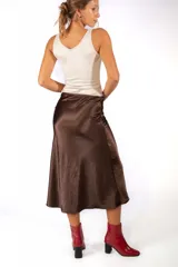 Body de color beige con escote en V profundo y diseño frontal con aberturas unidas por argollas metálicas doradas. Presenta breteles anchos y un ajuste al cuerpo.