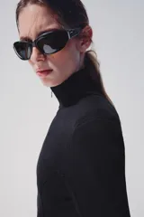 Chaqueta de punto negra con cuello subido y cierre frontal con cremallera, de manga larga y diseño ajustado.