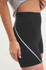 Calza tipo biker de tiro alto, color negro, con costuras laterales decorativas en color blanco. Confeccionada en tejido elástico de alto rendimiento.