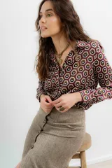 Camisa de crepe con estampado geométrico de hexágonos en tonos bordó, marrón y blanco. Presenta cuello camisero clásico, cierre frontal con botones y mangas largas con puños abotonados.