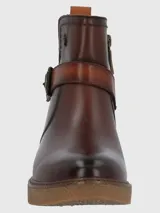 Bota corta de cuero vacuno color marrón con acabado envejecido, presenta una tira decorativa con hebilla metálica en el tobillo y una suela de plataforma de goma texturizada.