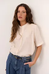 Camisa de manga corta color blanco con cuello mao y cierre frontal de botones. Presenta detalles bordados tono sobre tono en el canesú y diseño de corte recto.