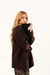 Tapado tipo poncho de color chocolate, confeccionado en tejido de paño, con cierre frontal completo metálico, cuello alto y bolsillos laterales.