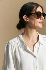 Camisa de manga larga color celeste, con cuello clásico, cierre frontal con botones y puños elastizados con volados. Presenta un diseño fluido con detalle de vainilla en la espalda.