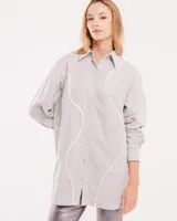 Camisa celeste de algodón con corte oversized, botones frontales a tono y vivos blancos ondulados en el frente.