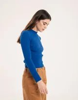 Pantalón de pana color verde oliva, de corte wide leg y largo al tobillo. Tiene cierre delantero con botón, bolsillos laterales y traseros.