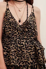 Top de tirantes finos confeccionado en viscosa con estampado animal print. Presenta escote en V con volados y diseño fluido.
