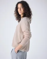 Sweater de punto fino color gris claro, con cuello en V y mangas largas. El tejido parece ser ligeramente transparente o muy liviano.