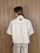 Sobrecamisa de denim soft azul, con cuello clásico, mangas cortas amplias, bolsillos frontales con solapa y cierre de botones metálicos.