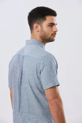 Camisa de manga corta confeccionada en mezcla de lino y algodón, color beige, con cuello camisero abotonado, bolsillo frontal en el pecho y cierre de botones.