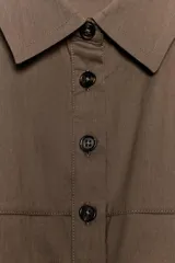 Vestido midi camisero color marrón, sin mangas, con cuello solapa y cierre frontal con botones. Presenta bolsillos delanteros con solapa y falda con pliegues en el bajo.