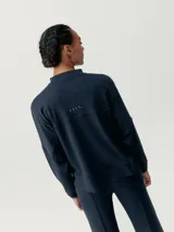 Chaqueta deportiva color azul marino, con cierre frontal, cuello alto y mangas murciélago. Presenta un calce holgado y bolsillos laterales.