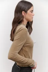 Polera de terciopelo color dorado, con cuello alto y mangas largas.