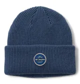 Gorro tipo beanie de tejido de punto acanalado en color azul oscuro, con vuelta y parche circular de la marca Columbia en el frente.