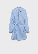Vestido camisero corto de diseño cruzado con cierre frontal de botones. Presenta estampado de rayas verticales en tonos azul, blanco y negro, cuello camisero clásico y mangas largas con puños abotonados.