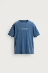Camiseta relaxed fit de color azul con efecto lavado, cuello redondo y manga corta. Cuenta con un estampado de texto a contraste en el delantero y acabados con efecto rotos.