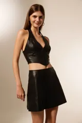 Top estilo corset de cuero sintético negro, con escote halter profundo y cierre frontal con alamares.