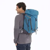 Mochila técnica Merrell modelo Grayling, diseñada para actividades al aire libre. Presenta un diseño ergonómico en color azul, con múltiples compartimentos con cierre, correas de ajuste laterales, cordones elásticos frontales para sujeción de equipo y logo de la marca estampado en la parte superior.