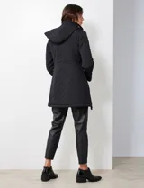 Campera capitoneada de corte largo con diseño de costuras multidireccionales, combinando un patrón de rombos en el cuerpo con capitoneado lineal en laterales y hombros. Cuenta con cierre frontal completo, cuello alto reforzado, capucha desmontable ajustable con cordones y bolsillos laterales con cierre invisible.