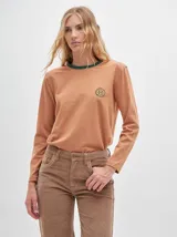 Remera de manga larga con cuello redondo y estampado a rayas horizontales en tonos marrón y negro. Tiene un logo bordado en el pecho de color rojo.