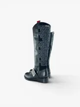 Bota de caña alta en cuero negro con punta redonda y taco bajo. Presenta un panel lateral de gamuza con bordado geométrico en hilo gris, herraje metálico decorativo en el empeine y cierre interno. El diseño cuenta con una boca asimétrica y forro interior de cuero.