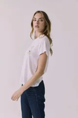 Remera blanca de manga corta y cuello redondo, con un estampado pequeño en el pecho que dice "Apres Tennis" en tonos verde lima y rosa.