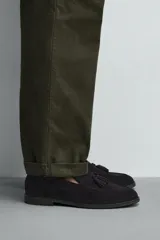 Mocasín de vestir negro confeccionado en piel con acabado serraje, con detalle de borlas en el empeine y ligero tacón.