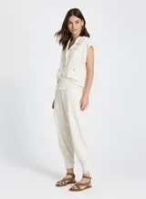 Pantalón jogger color crudo con estampado a cuadros, cintura con cordón ajustable, ribete elástico y minivolantes, bolsillos delanteros, detalles plisados y bajo con botones laterales.