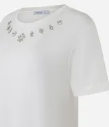 Remera blanca de viscosa con cuello redondo, mangas cortas y apliques de strass en el cuello.
