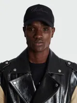 Gorra negra de algodón con visera y logo Balmain bordado en el frente.