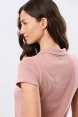 Remera polo de algodón color beige con mangas cortas, escote en V y cuello camisero. Presenta delicados mini bordados florales distribuidos en toda la prenda.