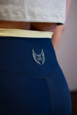 Calza corta deportiva color azul marino, tiro alto, con pretina ancha de color amarillo claro y un pequeño logo bordado en la parte trasera central superior.