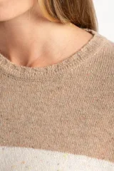Sweater de punto con diseño de rayas horizontales anchas en tonos beige y crema, con textura jaspeada. Presenta cuello redondo, mangas largas con puños acanalados y un corte holgado.
