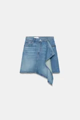 Falda de tiro medio confeccionada en denim, con trabillas, cinco bolsillos, cierre cruzado con botones y bajo acabado asimétrico.