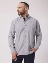 Camisa de manga larga con estampado de rayas finas verticales, cuello abotonado y cierre frontal con botones. Presenta un detalle de contraste en el interior del cuello y un pequeño logo bordado en el pecho.