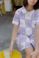 Vestido corto con estampado de cuadrados con peces y flores, cuello camisero y cierre frontal con botones.