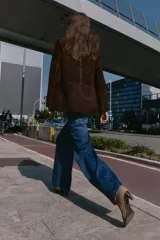 Blazer de piel 100% color marrón oscuro, con cuello solapa, manga larga con hombreras y bolsillos delanteros con solapa. Presenta pespuntes decorativos en contraste y cierre frontal con un botón.