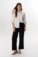 Camisa verde militar de manga larga con puños color crema, cuello clásico y cierre frontal con botones. Tiene un bolsillo en el pecho con bordado de una palmera color crema.